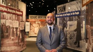 A museum curator stands in front of a colorful exhibit devoted to Washington DC history